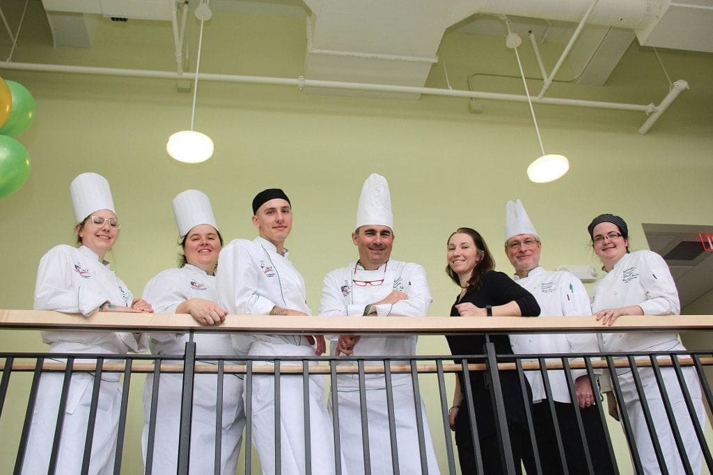 faculty and staff stand on the second-floor landing of the new HCC MGM Culinary Arts Institute