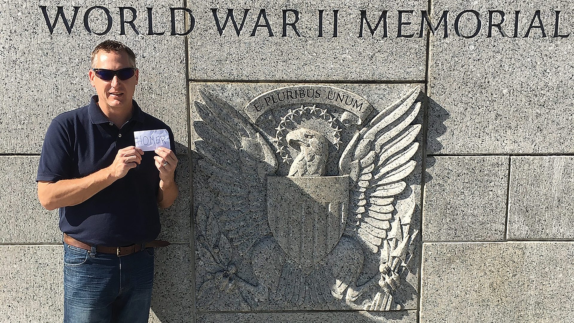 Dr. Mark Kenton holds up a card with the name ‘Homer’ on it at the World War II memorial