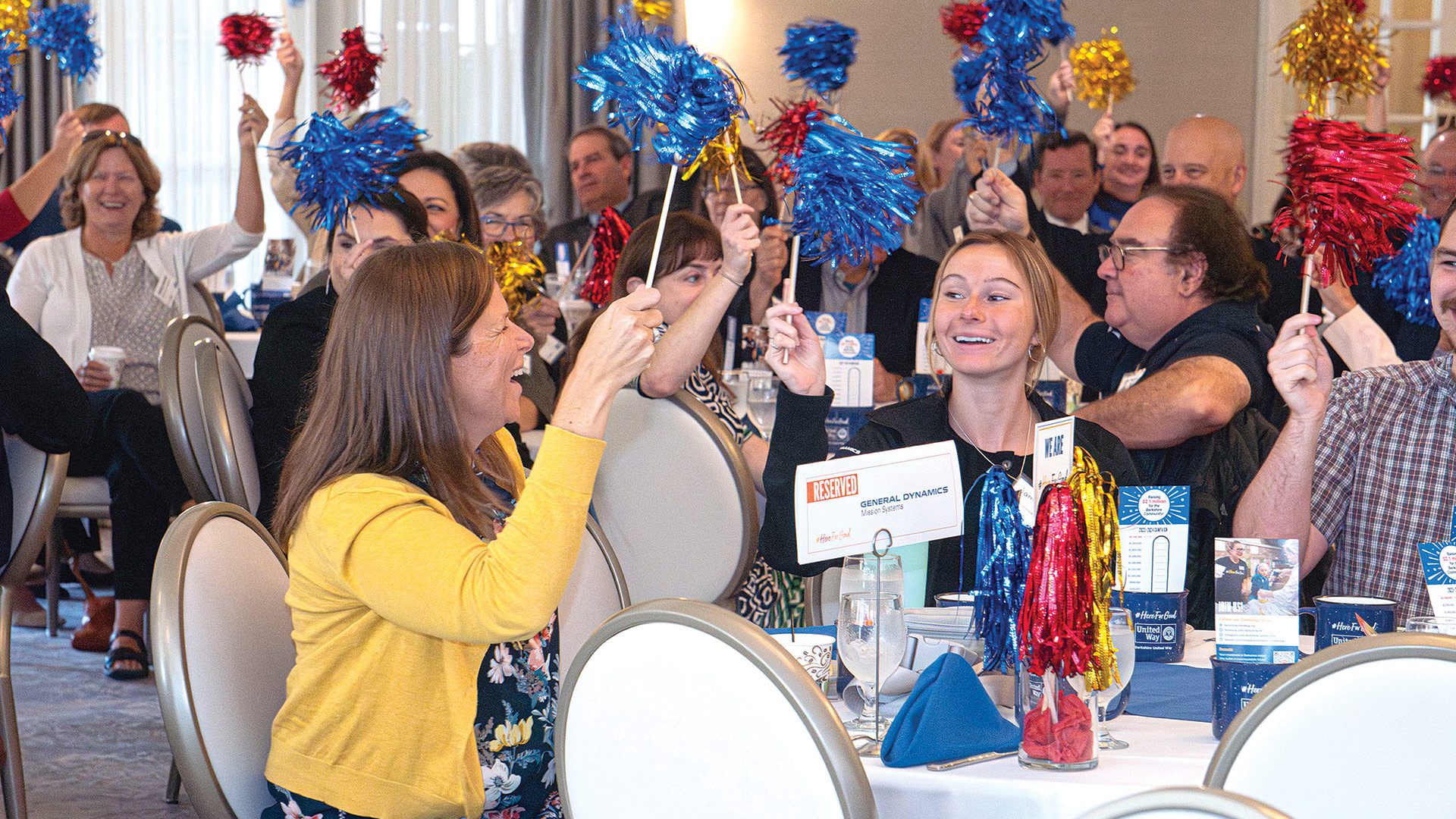 attendees wave pom-poms during a celebratory moment. (Photo by Autumn Phoenix Photography)