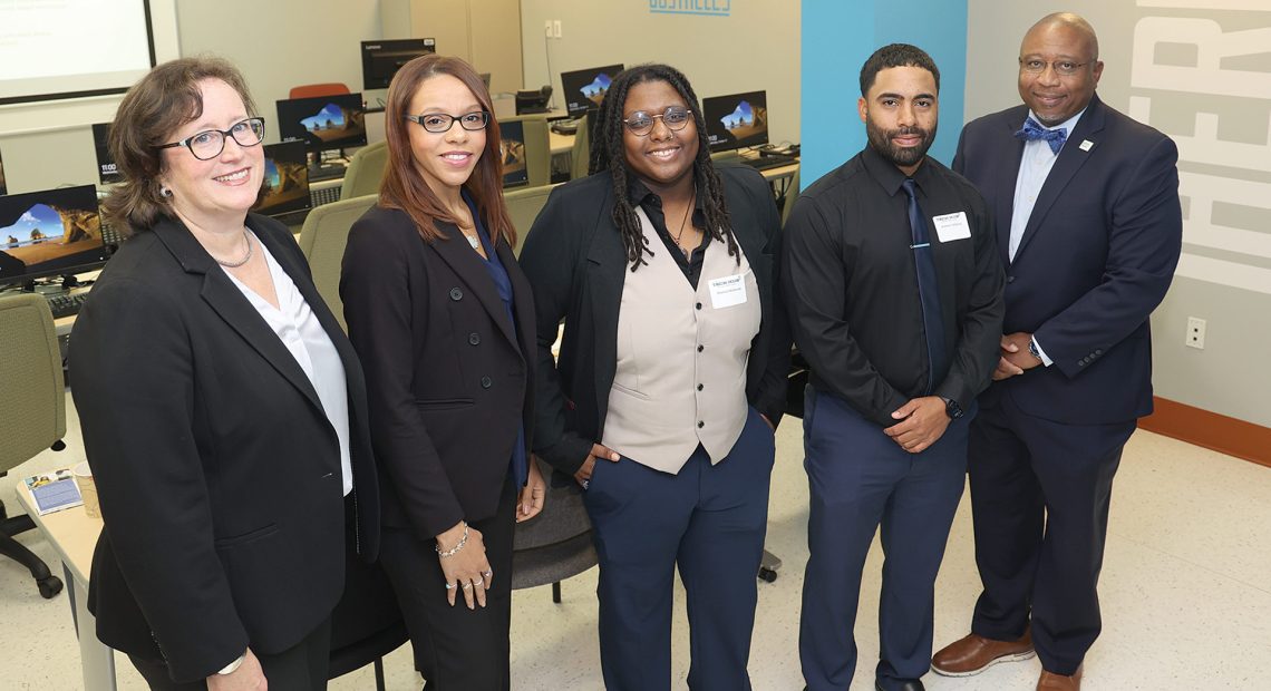 Tricia Canavan (far left) and HCC President George Timmons (far right) in the Tech Hub digital classroom with Tech Foundry graduates (and current Tech Hub fellows) Lasharie Weems, Shanice McKenzie, and Anelson Delacruz.