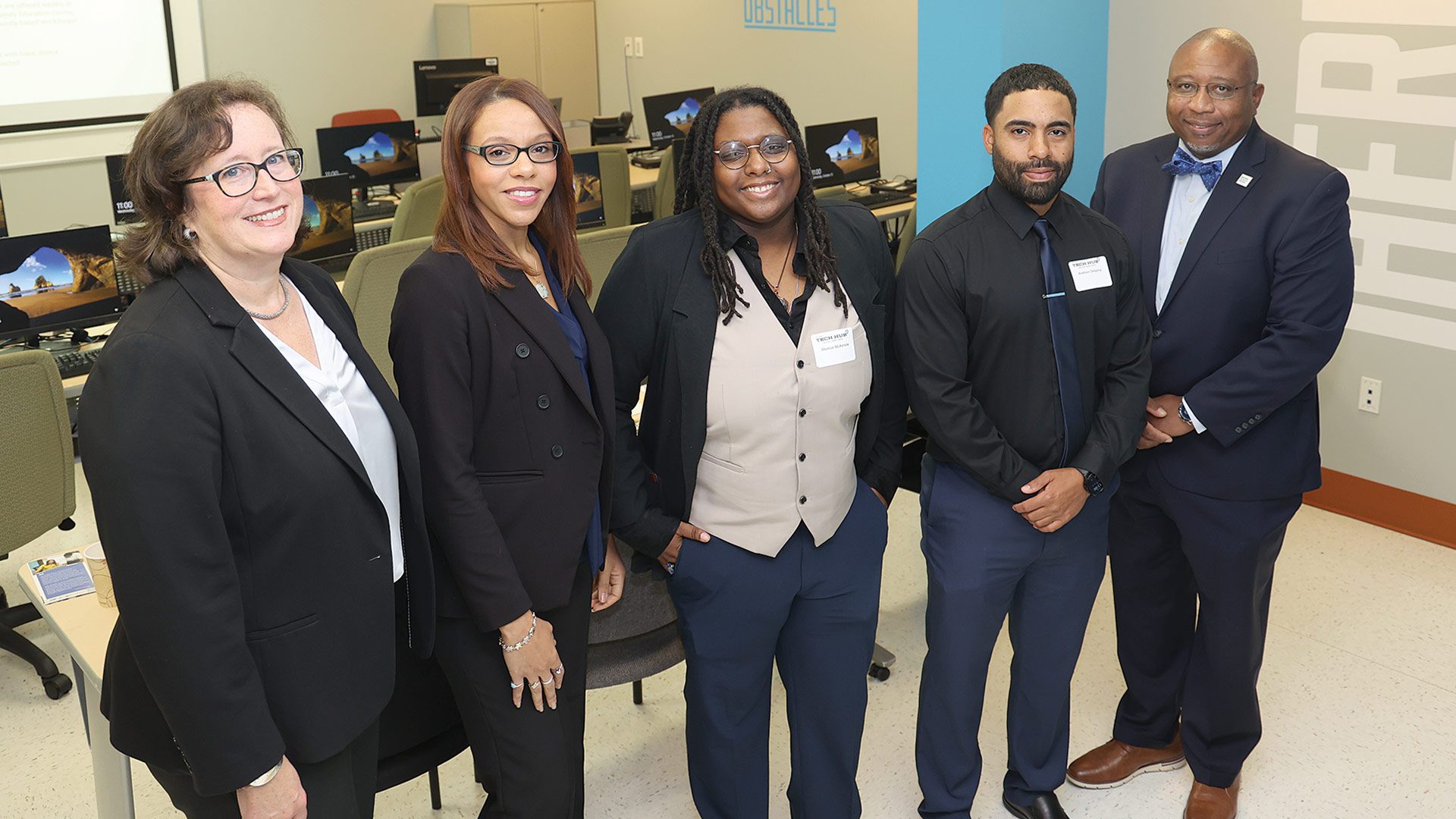 Tricia Canavan (far left) and HCC President George Timmons (far right) in the Tech Hub digital classroom with Tech Foundry graduates (and current Tech Hub fellows) Lasharie Weems, Shanice McKenzie, and Anelson Delacruz.