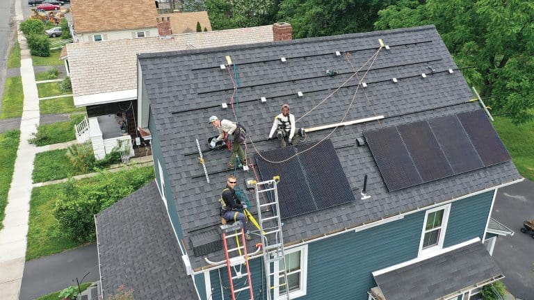 PV Squared workers install solar panels on a house.