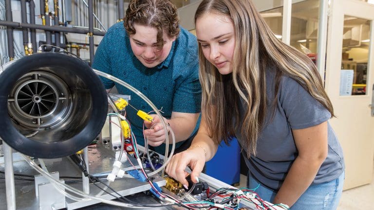 Two Western New England University students work on a jet engine they built